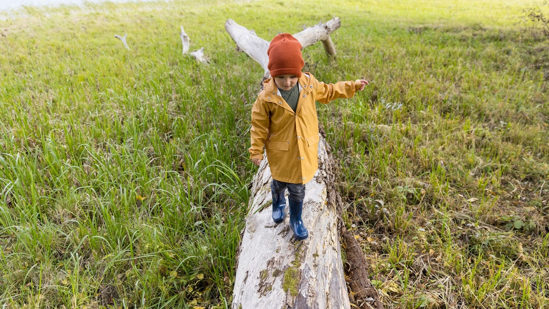 Kid in raincoat staying on the lumber